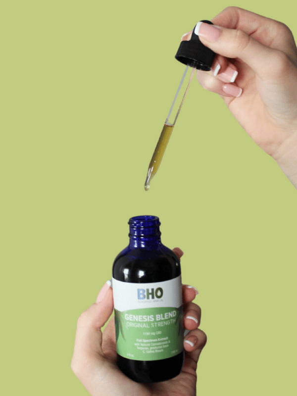 A content individual holding a dropper filled with Genesis Blend CBD Oil, ready to administer sublingually for a wholesome wellness routine.